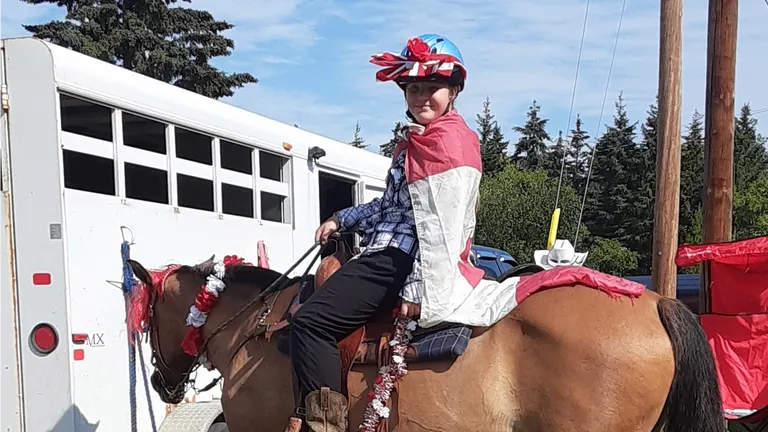 Girl in costume on buckskin horse.